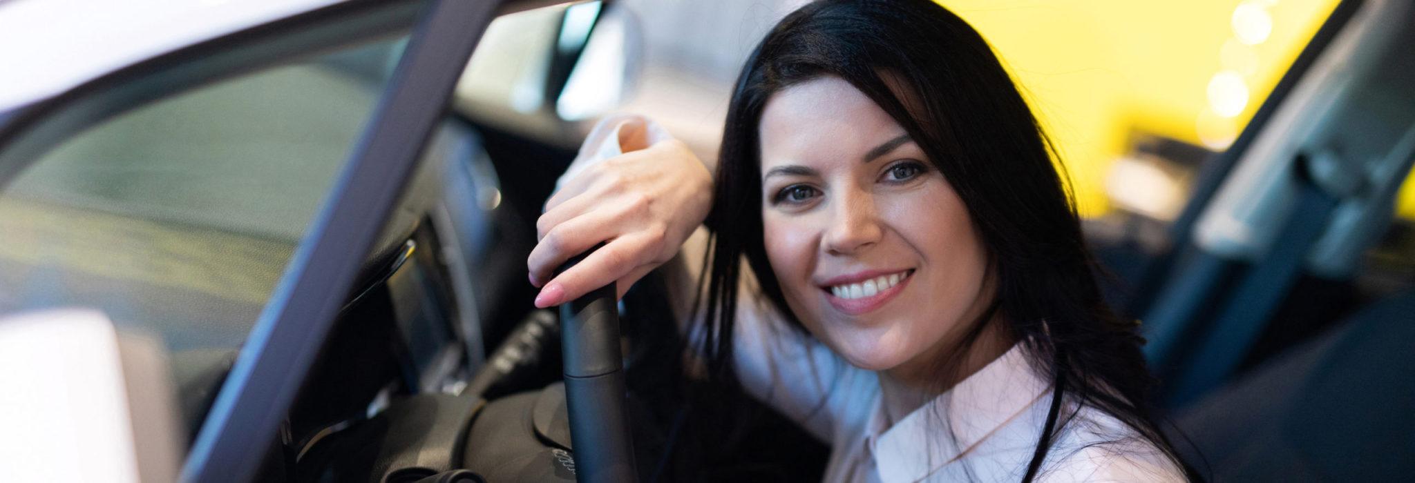 Happy customer woman buying a new car in dealership center